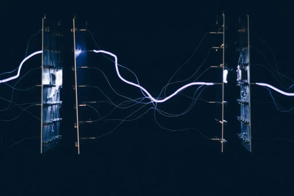 Na imagem dois painéis metálicos mostram faíscas azuis e brancas de diferentes cargas elétricas.