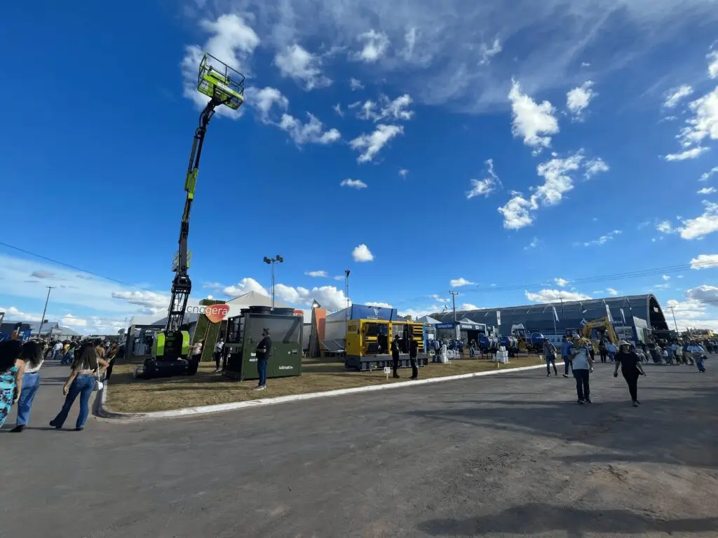 Na Bahia Farm Show, os visitantes aproveitaram as oportunidades do agronegócio sob um céu azul com algumas nuvens. As pessoas circularam entre grandes máquinas, como uma plataforma elevatória verde e equipamentos amarelos, tiraram fotos e conferiram os estandes repletos de novidades em maquinário. A Tecnogera está presente levando soluções inovadoras para o setor.