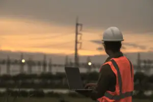 Ao fundo, postes e linhas de energia se destacam sob um céu amarelo alaranjado com nuvens, ilustrando como a infraestrutura energética pode influenciar a reputação das empresas.