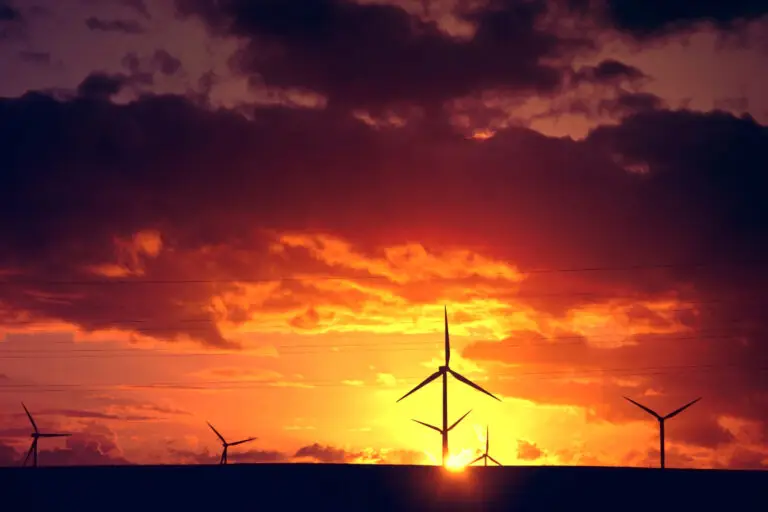 Turbinas eólicas, símbolos das energias renováveis, aparecem em destaque sob pôr do sol impressionante