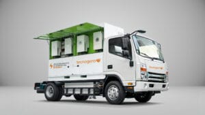 Caminhão branco BESS da Tecnogera com equipamento de baterias e soluções híbridas, painel verde aberto. Fundo cinza claro.