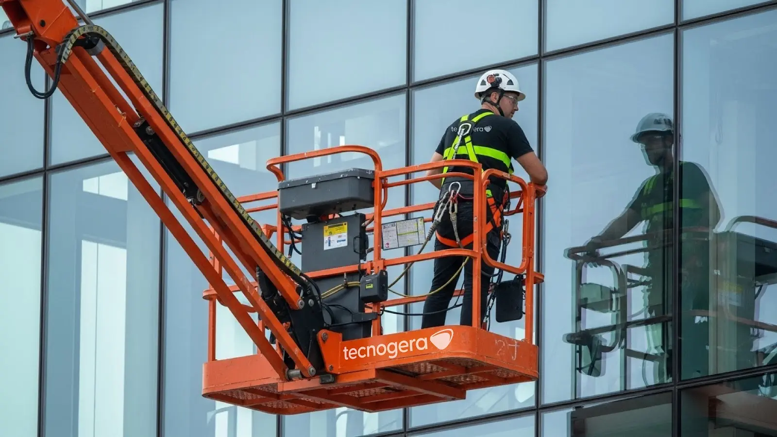 Plataforma elevatória articulada da Tecnogera em fachada de vidro