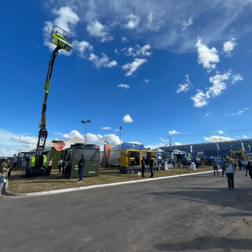 Na Bahia Farm Show, os visitantes aproveitaram as oportunidades do agronegócio sob um céu azul com algumas nuvens. As pessoas circularam entre grandes máquinas, como uma plataforma elevatória verde e equipamentos amarelos, tiraram fotos e conferiram os estandes repletos de novidades em maquinário. A Tecnogera está presente levando soluções inovadoras para o setor.
