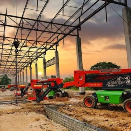 Plataforma elevatória em um terreno de terra sob uma estrutura de aço ao entardecer